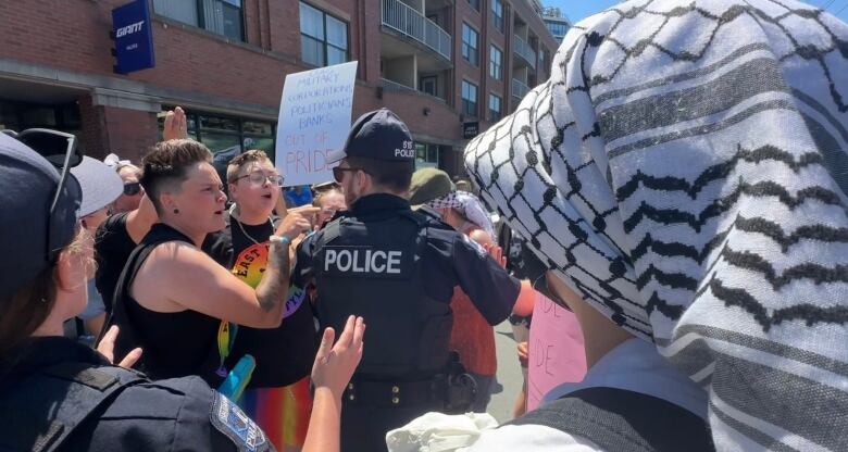 A police officer stands in the middle of an angry crowd. 