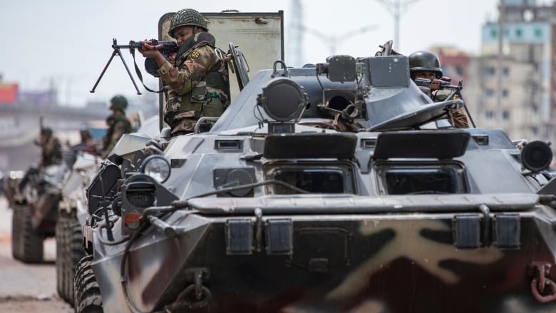 Two soldiers in a tank point their weapons.