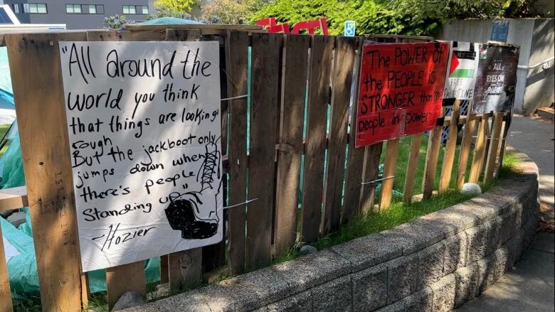 Signs at the VIU encampment from June 11. One of them reads 'All around the world you think that things are looking rough. But the jackboot only jumps down when there's people standing up