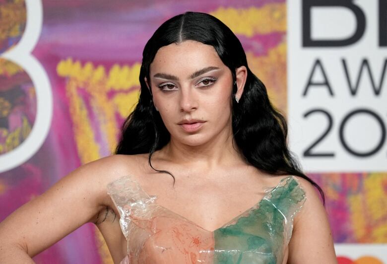 A woman in a colourful dress poses for cameras.