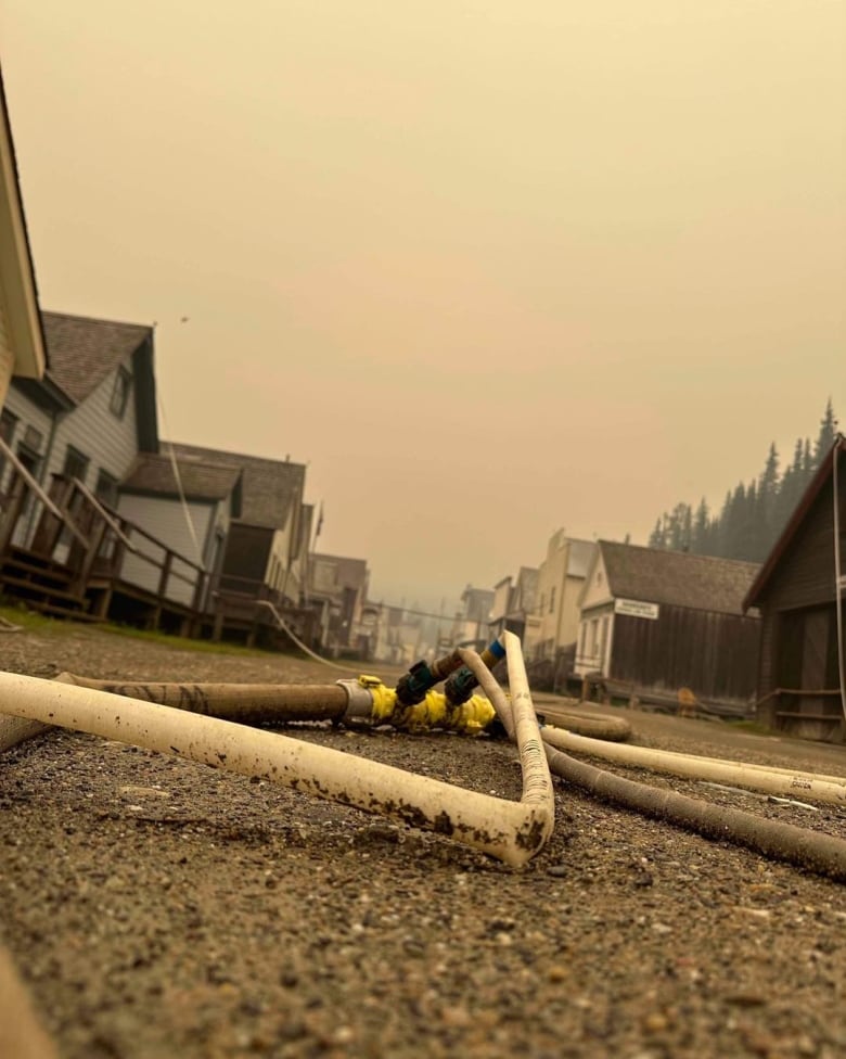 Pipe on a dirt road surrounded by wooden buildings.