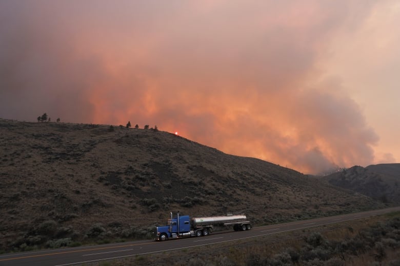 A truck drives in front of a smoky sky.