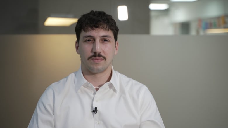 A man with a thin moustache, wearing a white shirt. 