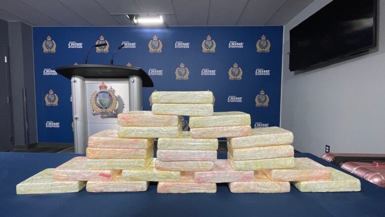 White bricks of packaged cocaine are seen stacked on a table.