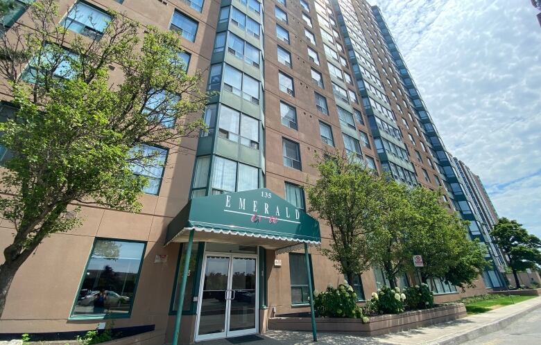 Exterior of a brown condo building with a green awning above the front entrance. 