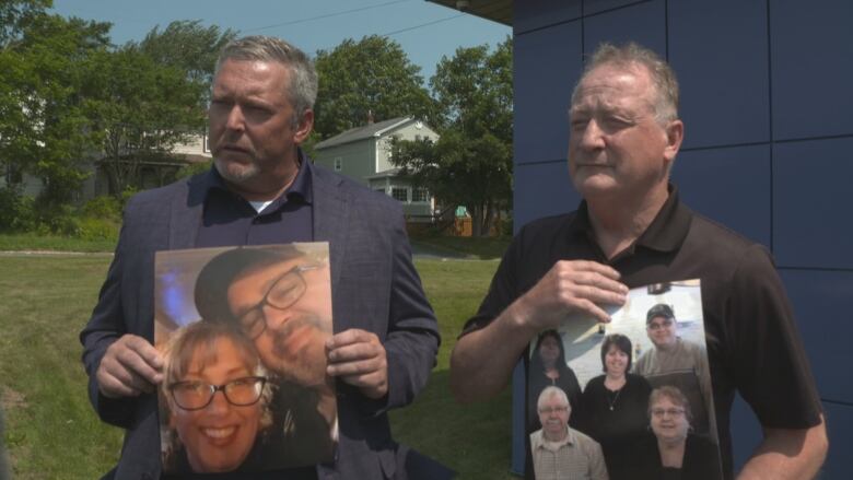 Two men hold images of family members of a fatal explosion victim.