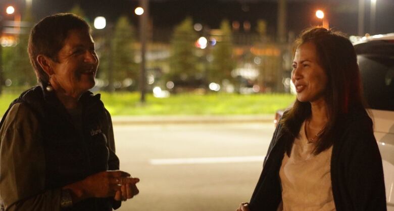 two women standing near each other talk 