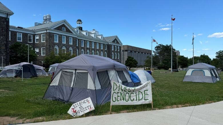 A group of tents with signs in front them and university buildings in the background 