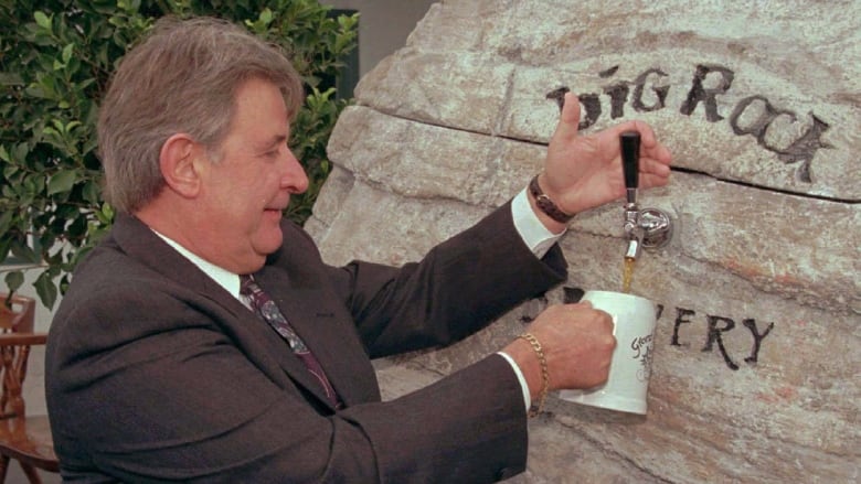 A man pulls beer from a spout attached to a rock that reads Big Rock Brewery.