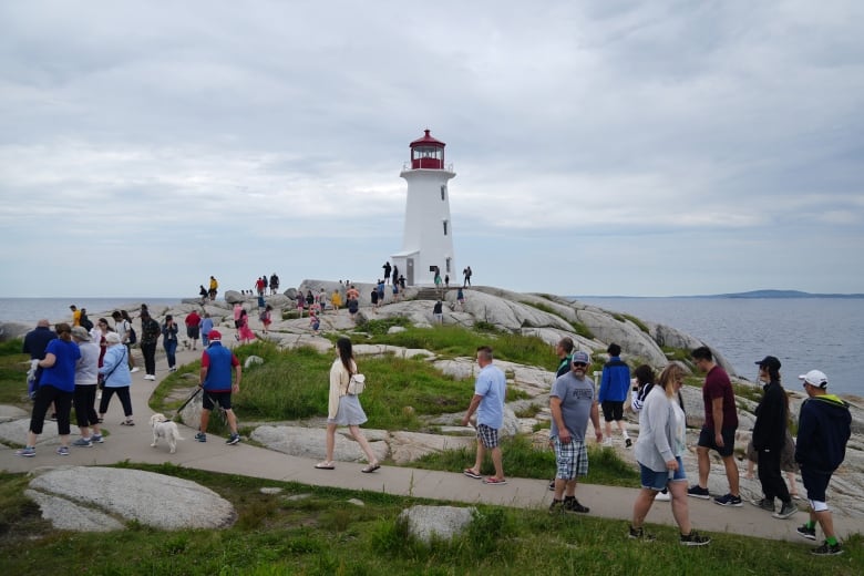 Tourists visit the lighthouse in Peggy's Cove, N.S. on Canada Day, Friday, July 1, 2022. Canada is struggling to get back into the top 10 most-visited countries by tourists.