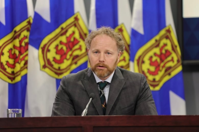 A man in a suit speaks into a microphone.