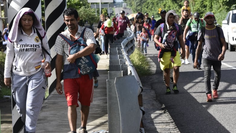 Migrants walk along the highway through Suchiate, Chiapas state in southern Mexico, Sunday, July 21, 2024, during their journey north toward the U.S. border.