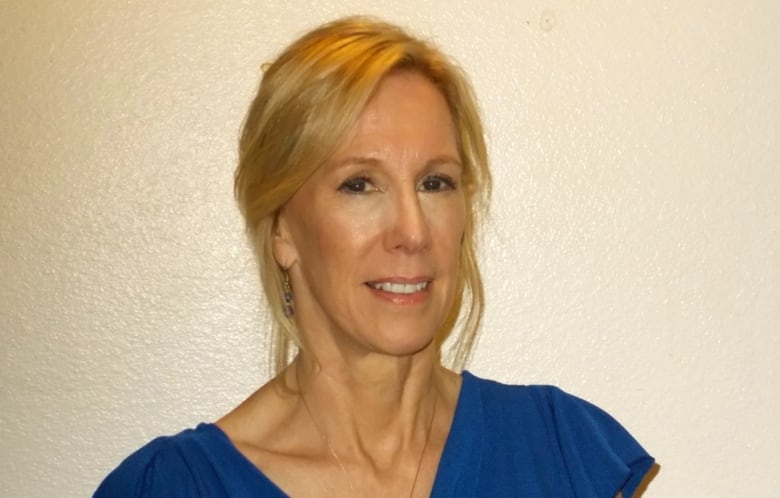 A blonde woman with a red blouse smiles at the camera.