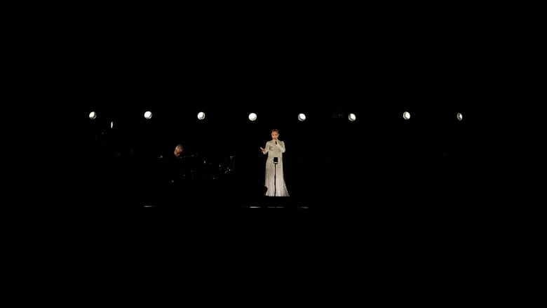 A woman in a white dress sings at night.