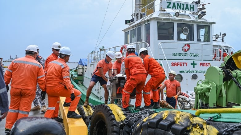 Coast guard personnel load skimmers at a port.