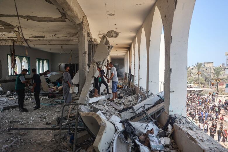 People inspect the damage inside a destroyed building.