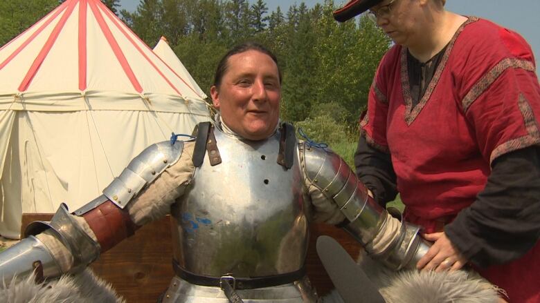 A woman gears up for a joust. 