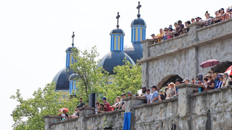 A group of spectators are seen on the side of a castle.