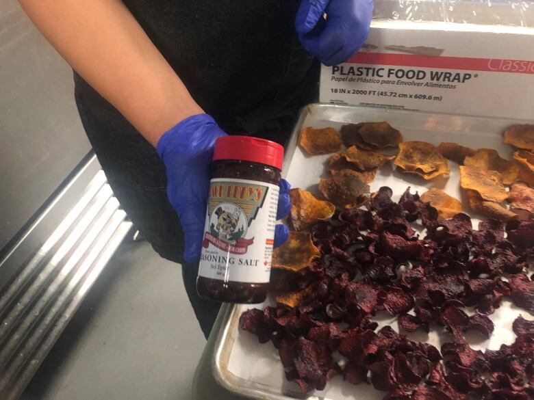 Woman in chef uniform holds jar of Back Eddy's seasoning