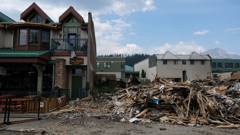 An undamaged building stands next to the rubble of another building.