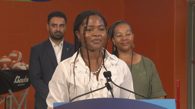 A girl stands in front of a microphone and podium at a news conference.