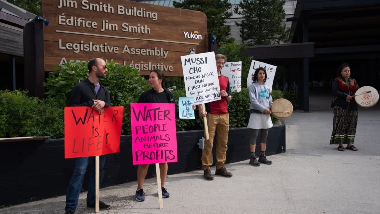 People protest with signs in front of a legislature 