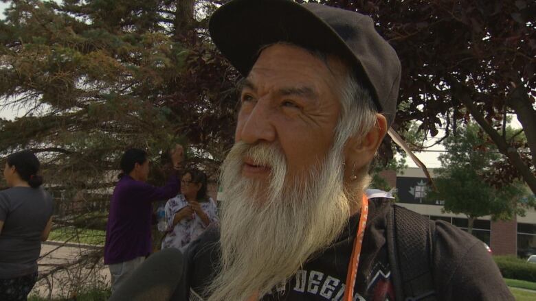 Man with a white beard and a cap looking at the camera