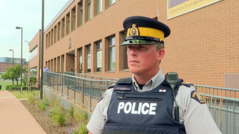 Police officer stand inront of brick building during interview.