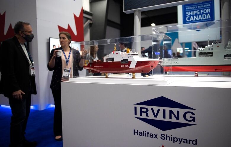 A model of a red and white ship sits in a plexiglass display case on a pedestal that says 