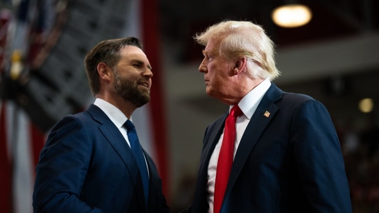 Two men in suits shake hands and look into each other's eyes