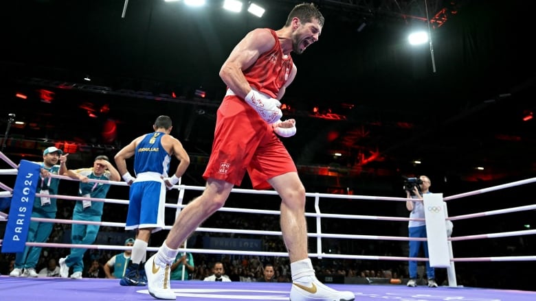 A men's boxer clenches his fists and yells in celebration