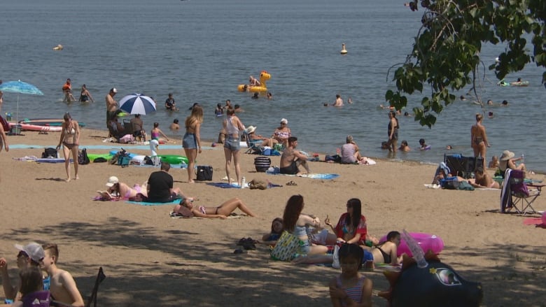 Swimmers and beachgoers at Regina Beach on a hot, summer day.