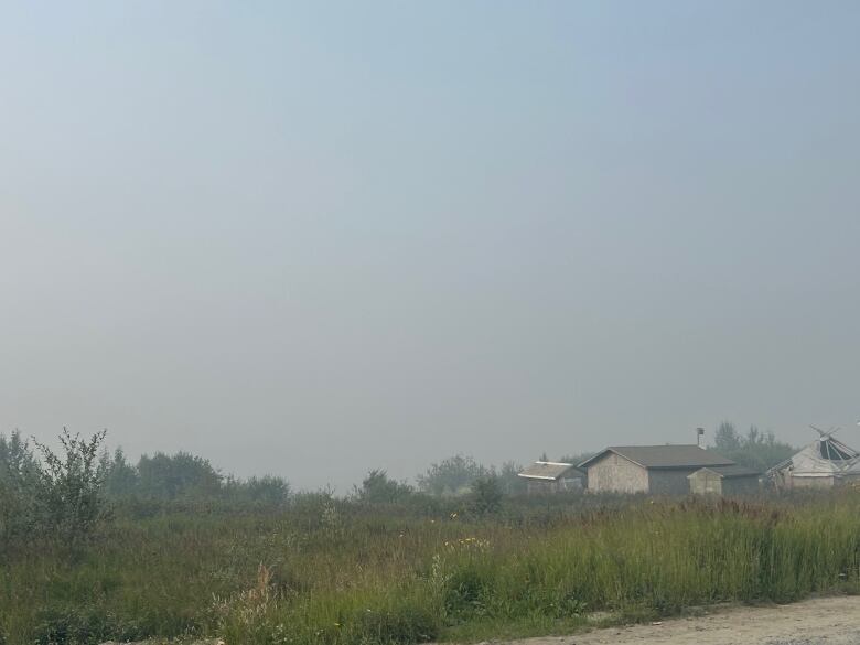 Houses sit on a field covered with wildfire smoke.