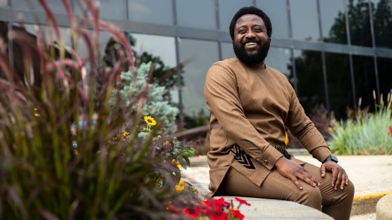 A man sits by fowers.