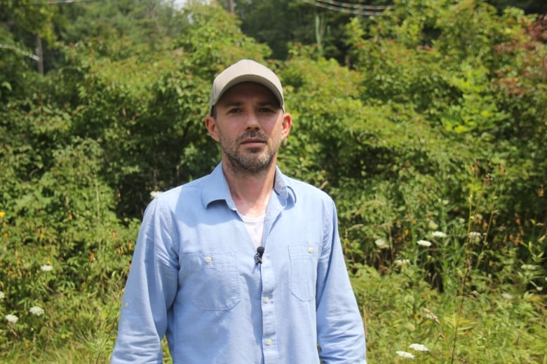 A man wearing a cap looks at the camera