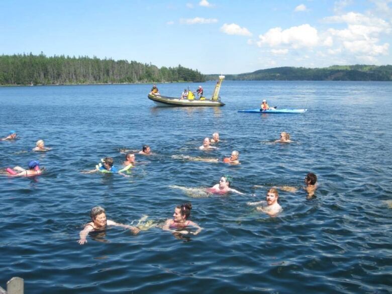 A photo shows about a dozen swimmers participating in Swim The Canal.