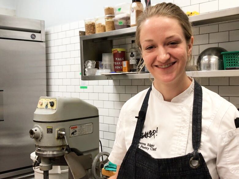 A pastry chef stands beside a mixer in the kitchen