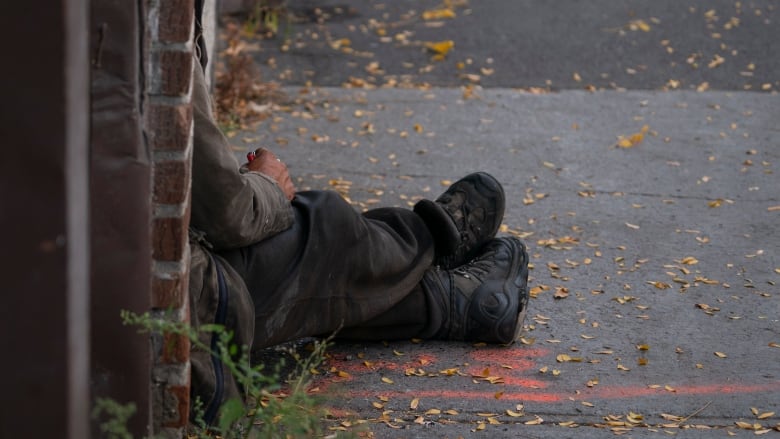 A person's legs stick out from a doorway on a street.