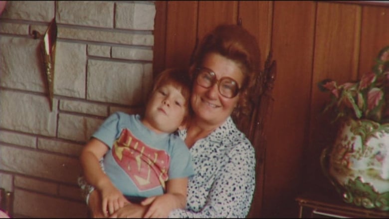 A young child is sitting on the lap on an elderly woman. 