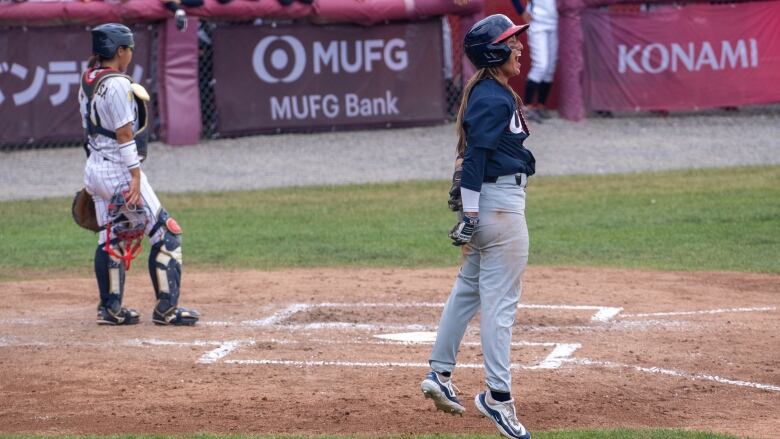 A woman celebrates hitting a home run by jumping into the air. 