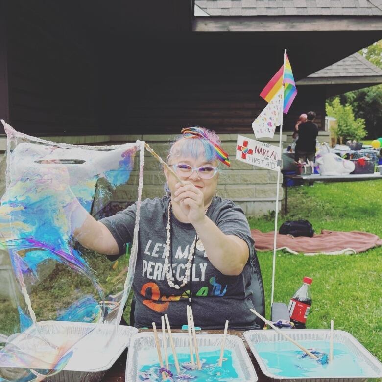 A woman blows a large bubble at a table.