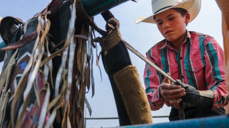 A young cowboy prepares his gear for rodeo.