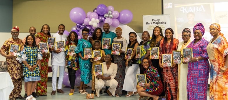 A large group of people holdup a magazine to the camera and smile.