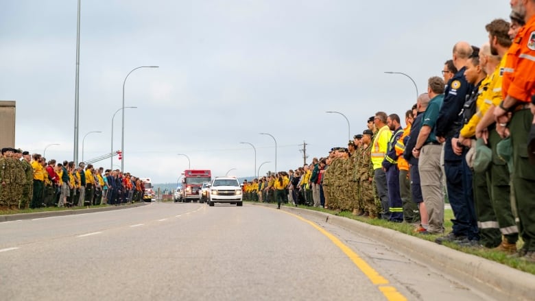 Firefighters line a highway to honour a fallen comrade.