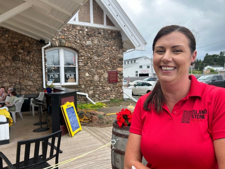 Server stands in front of outdoor tables.