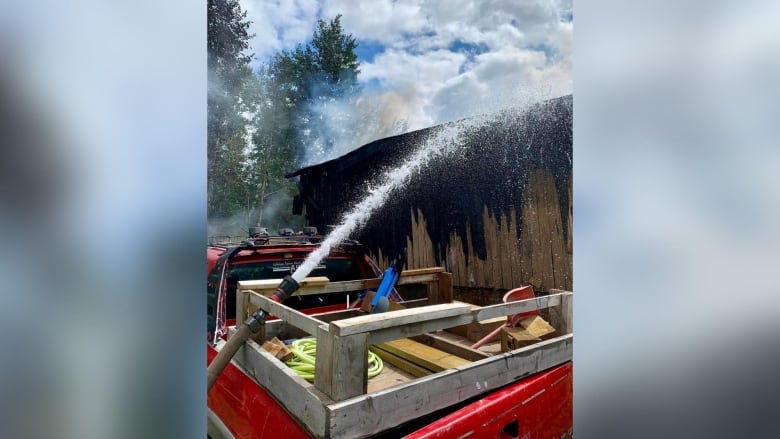 Water is seen spraying the outside of a burnt log structure.