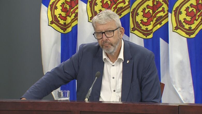 man sits next to nova scotia flags.