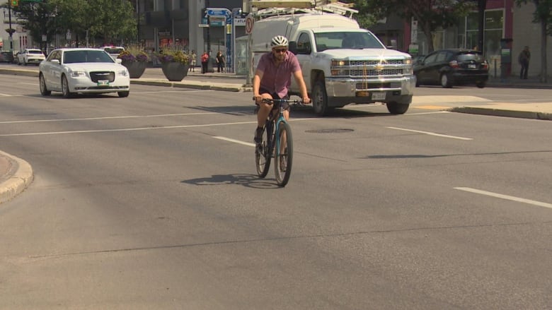 A man is riding a bike down a busy street.