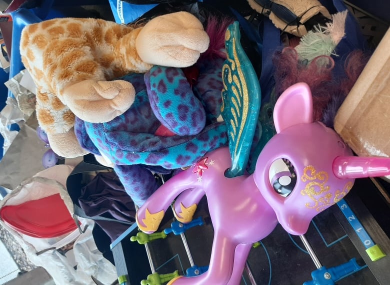 A bin full of toys including a purple unicorn.