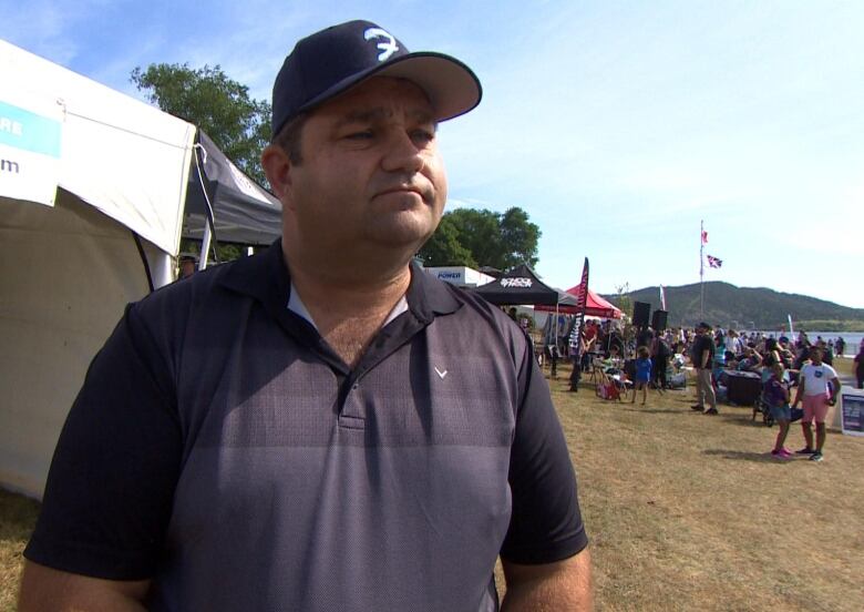 A man in a polo shirt stands in front of a crowd